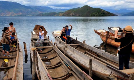 Tourists take photos beside the Lugu Lake: in 2012, 1.5 million tourists visited the region, nearly three times as many as the previous year. Photograph: Chen Haining/Xinhua Press/Corbis